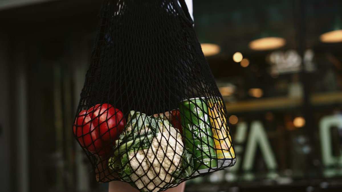 Close-up of vegetables and a can in a net bag, emphasizing eco-friendly shopping.